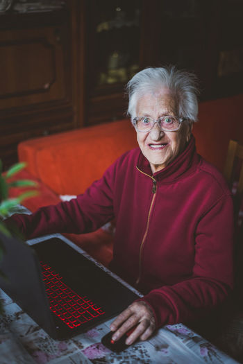 Portrait of smiling senior woman using laptop while sitting at home