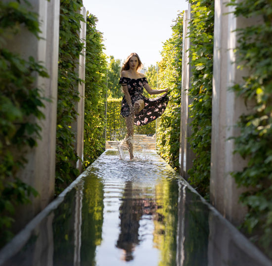 Woman standing on walkway against plants