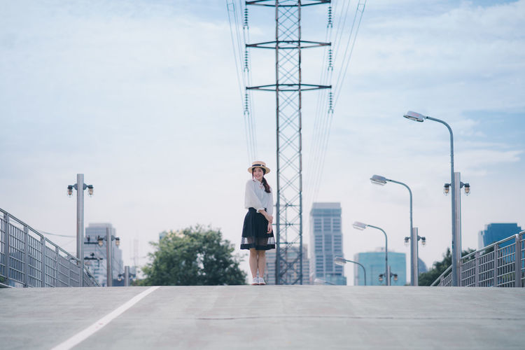Full length of woman standing on road against sky in city