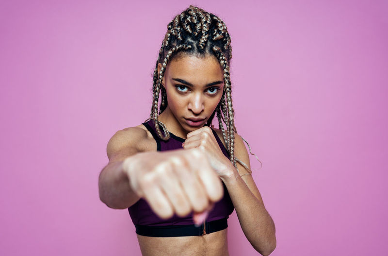 Portrait of woman showing fist against colored background