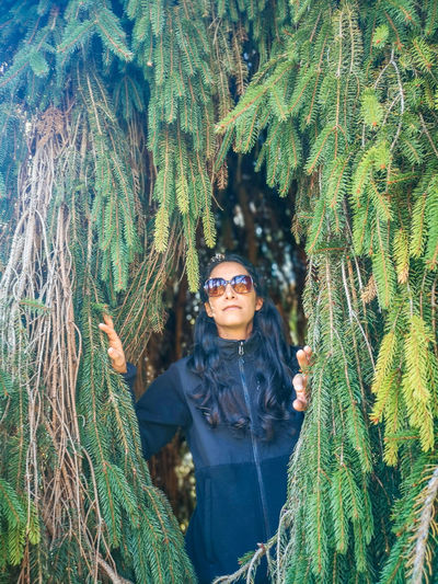Young woman wearing sunglasses standing by plants