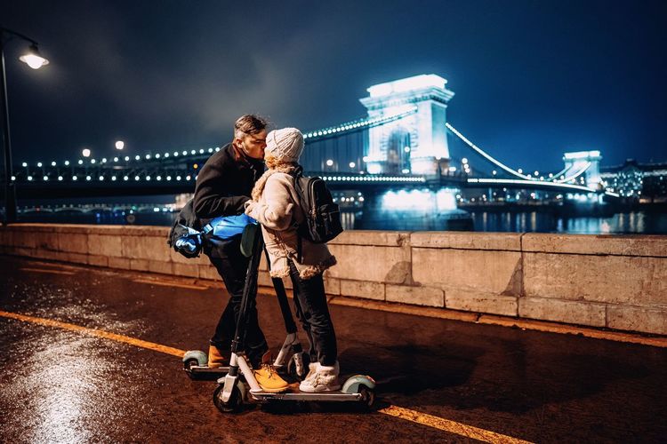 Couple kissing on bridge in city at night
