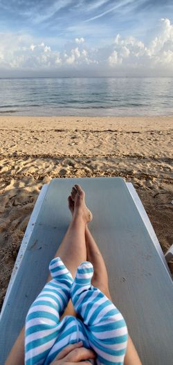 Point of view faceless shot of mother and baby legs on a beach chair by the ocean 