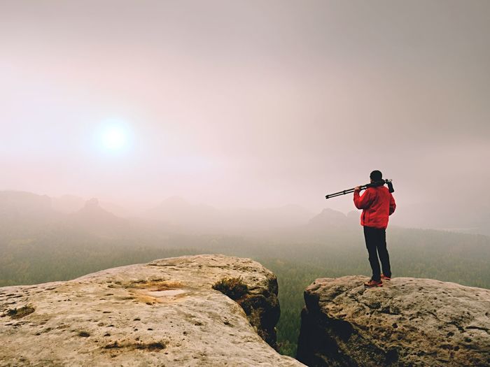 Photographer think about picture on peak in the misty mountains. landscape view of man