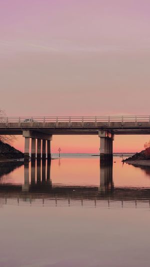 Bridge over water against sky during sunset