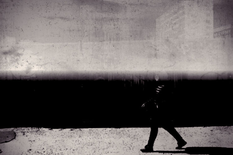 Silhouette man walking on wall in city