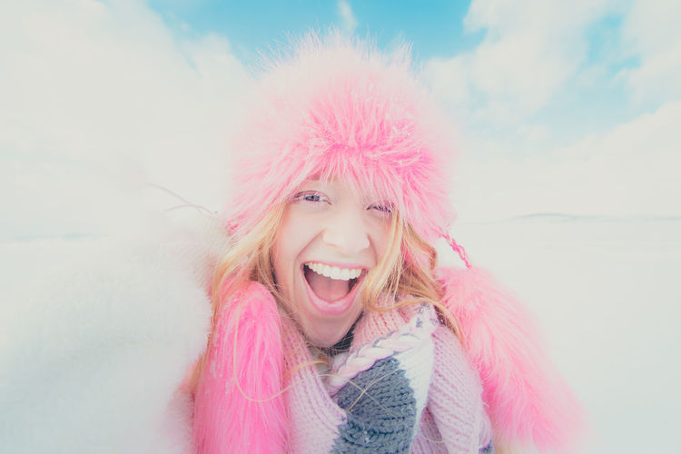 Portrait of young woman with pink hat against sky