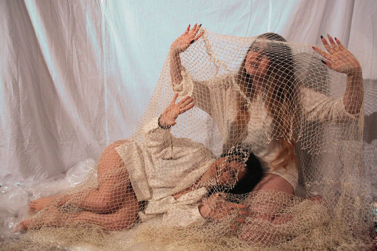 Women trapped in fishing net against curtain
