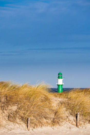 Lighthouse on beach against sky