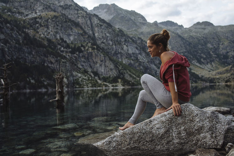 Woman sitting on rock looking at mountains