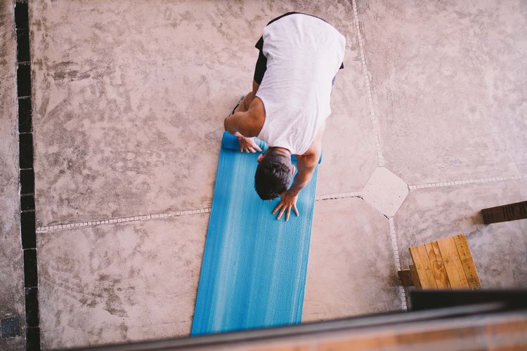 High angle view of man rolling exercise mat at yoga studio