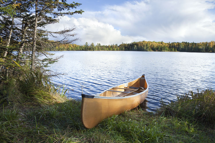 Boat moored at lakeshore against sky