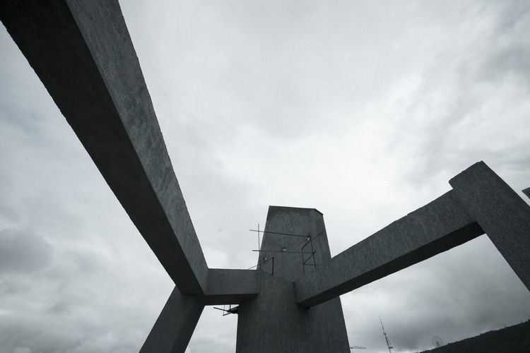 Low angle view of cross on bridge against sky