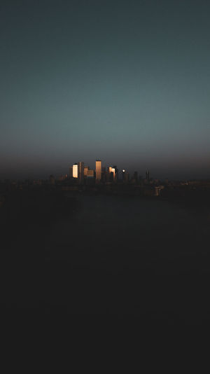 City buildings against clear sky at dusk