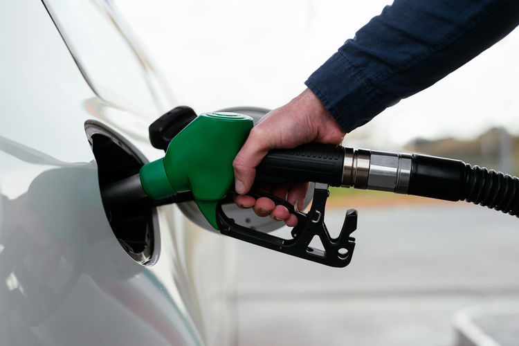 Cropped unrecognizable man refilling vehicle tank at petrol station during energy crisis