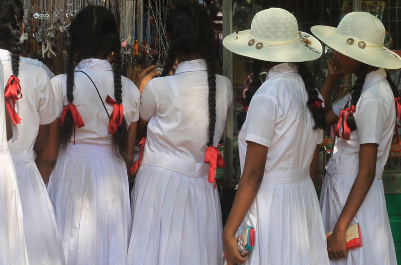 Rear view of schoolgirls shopping in market