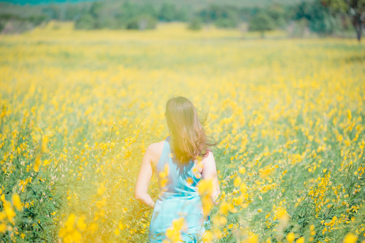 Woman with yellow flower in field