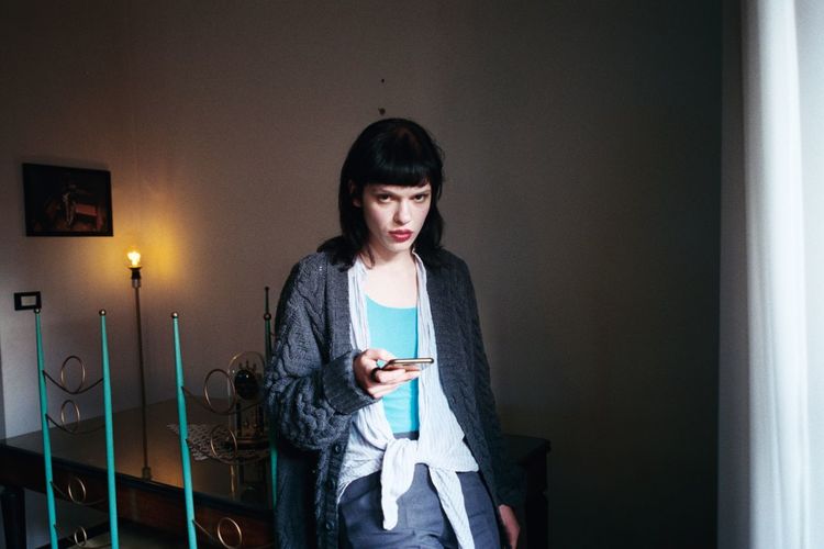 Young woman using phone while standing on mirror