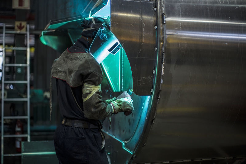 Man welding steel tank in factory