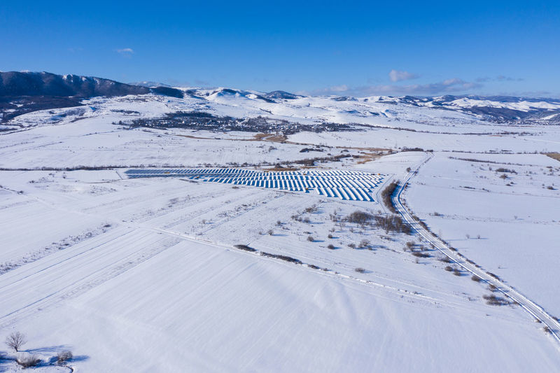 Aerial drone view of snow covered solar panel park, photovoltaic power station in the winter