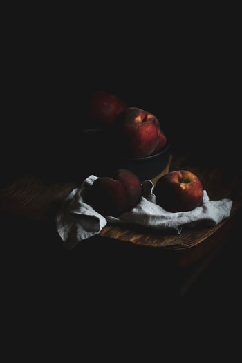 Cropped image of hand holding apple against black background