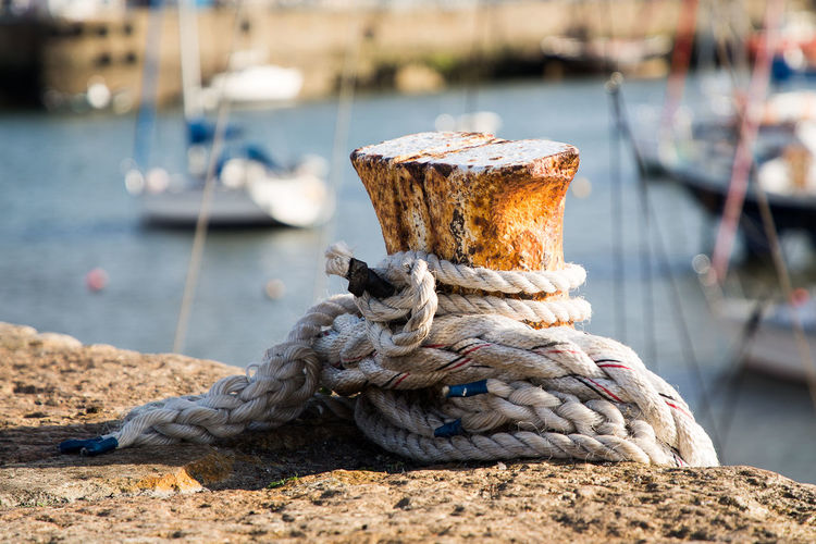 Close-up of rope tied on bollard at harbor
