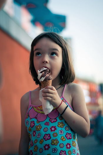 Cute girl looking up while eating ice cream