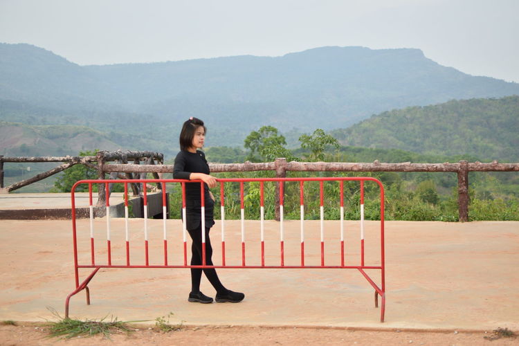 Full length of woman standing by railing against mountains
