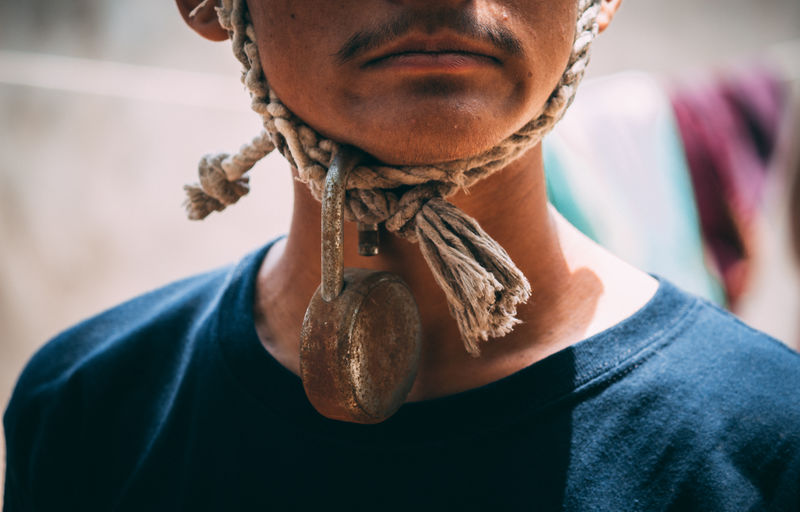 Midsection of man with rusty padlock hanging from rope