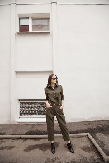 Female fashion model, posing for a full length photo, wearing green suit, urban fashion photography
