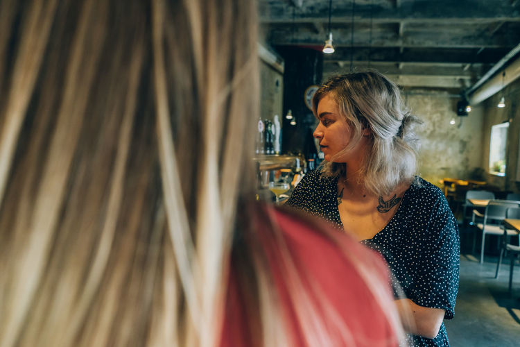 Two blonde girlfriends in a cocktail bar.