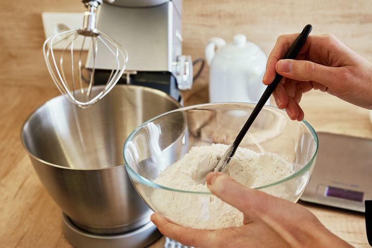 Woman pours flour into a mixer bowl