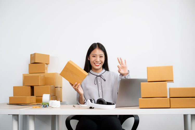Cheerful woman holding parcels while sitting at office