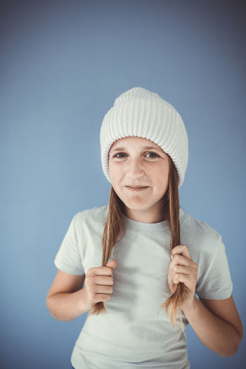Portrait of smiling young woman wearing hat against blue background