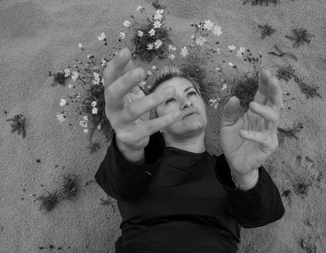 High angle view of woman gesturing while lying on sand