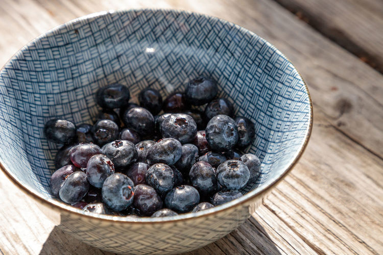 Organic blueberries in a blue and white bowl on the rustic wood background of an old farm table