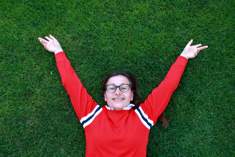 Portrait of smiling boy with arms raised on grass