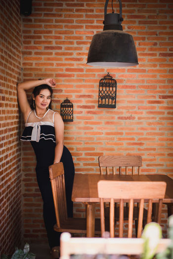 Portrait of woman standing against brick wall