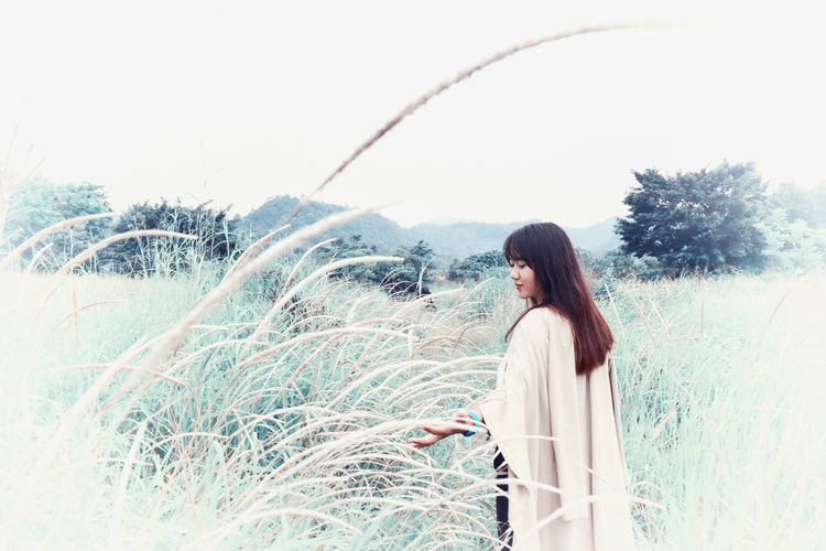 Young woman standing amidst grass on land