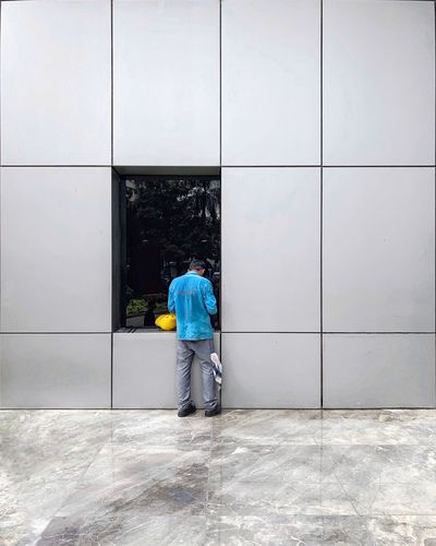 Rear view of man walking on floor against building