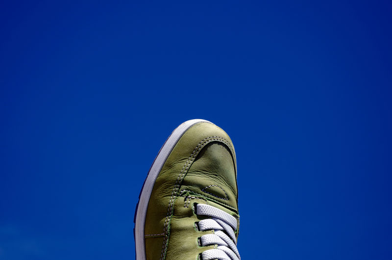 Low section of legs against clear blue sky