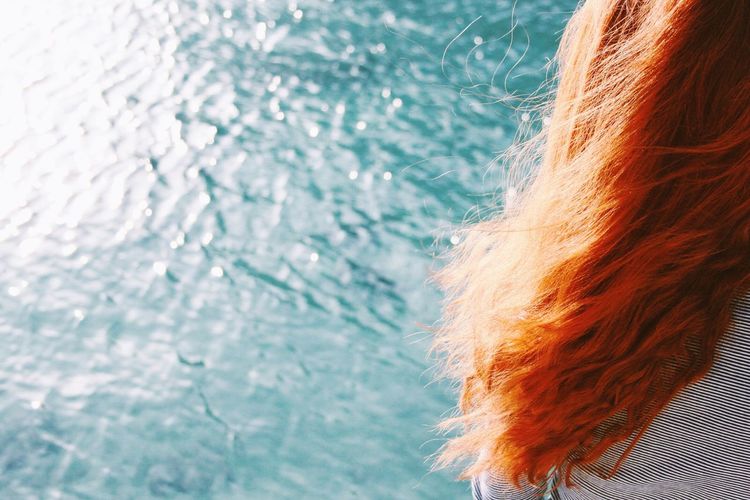 Cropped image of redhead woman against lake