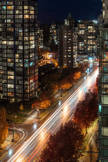 High angle view of light trails on street amidst buildings at night
