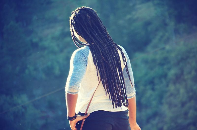 Rear view of young woman with dreadlocks standing outdoors