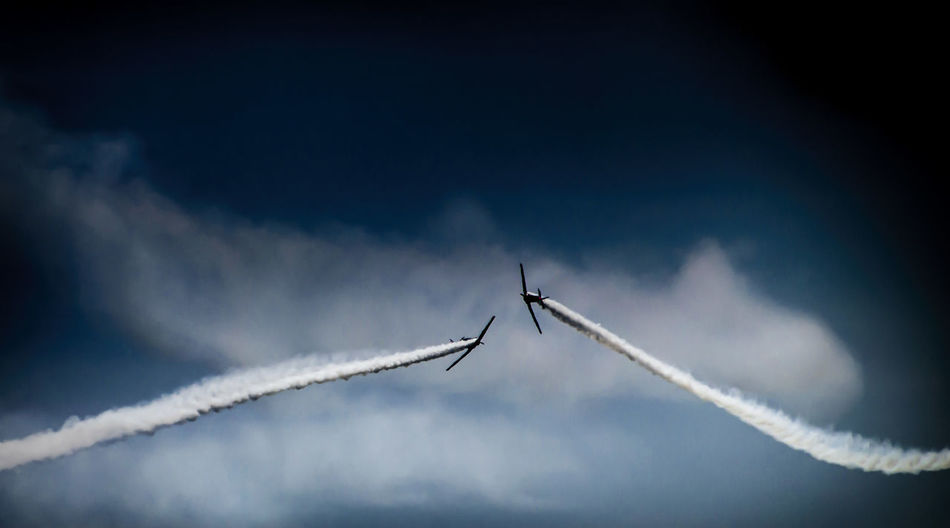 Low angle view of airplanes with trails in flight