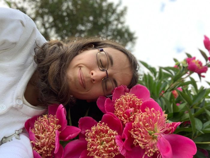 Woman with eyes closed by pink flowers