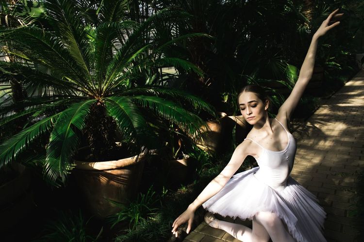 Ballet dancer dancing against palm trees
