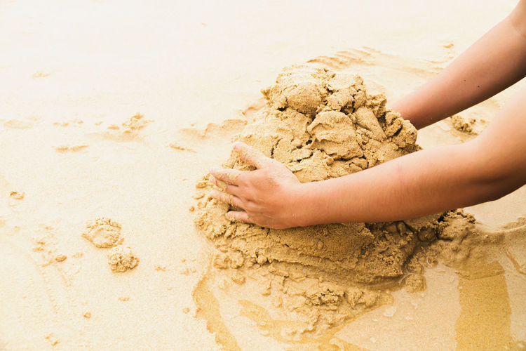 Cropped hand of woman holding sand at beach