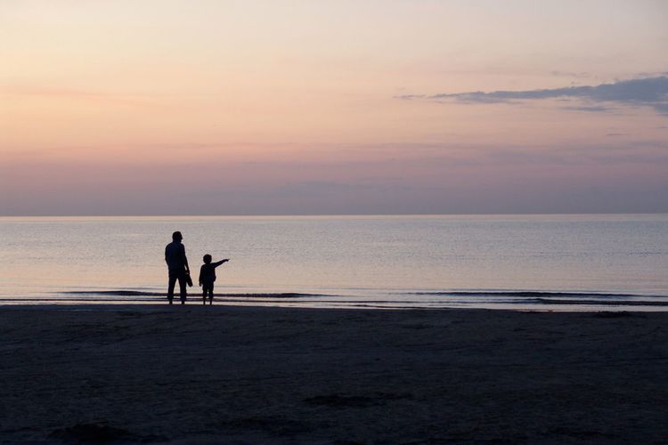 Two silhouette people on calm beach