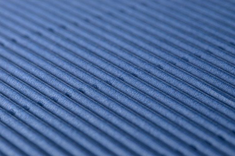 Background made of blue corrugated cardboard with diagonal stripes, shallow depth of field.